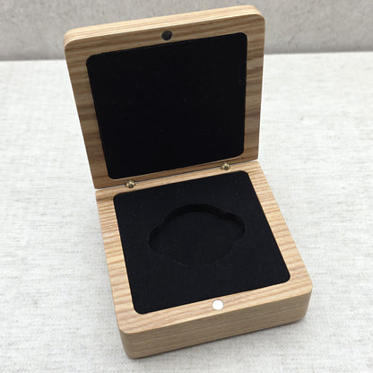 High angle view of open light-colored wooden gift box featuring matching black velvet-covered foam insert for challenge coins and medals.